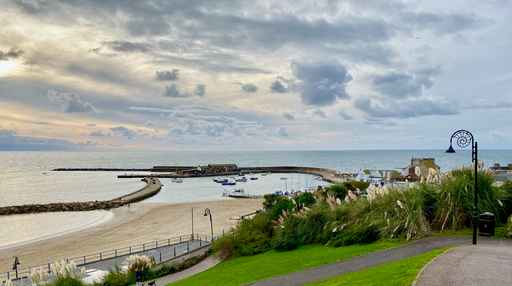 Overlook of a harbour, breakwater, and beach at dusk.