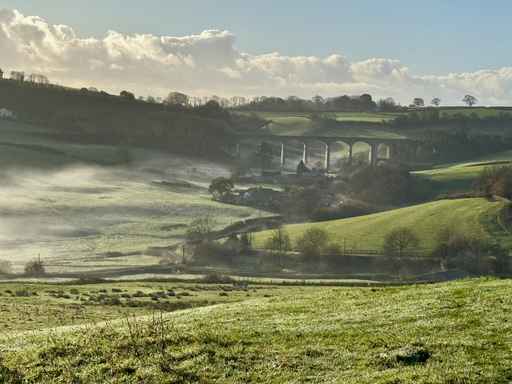Misty rolling green hills and a distant railway viaduct.