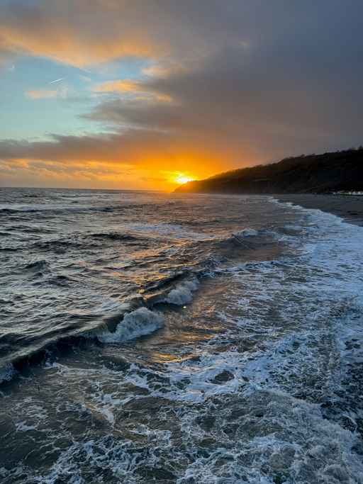 Ocean waves rolling ashore at sunset.