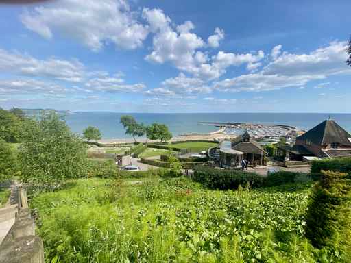 Elevated view of lush green hills overlooking a seaside town and harbour.