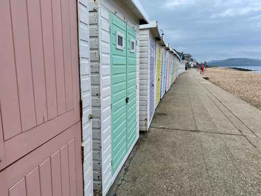 Row of colorful beach huts along a concrete promenade.