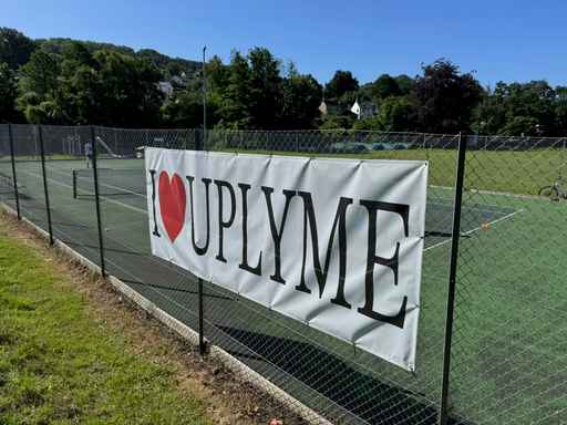 'I LOVE UPLYME' banner on a sports field fence.